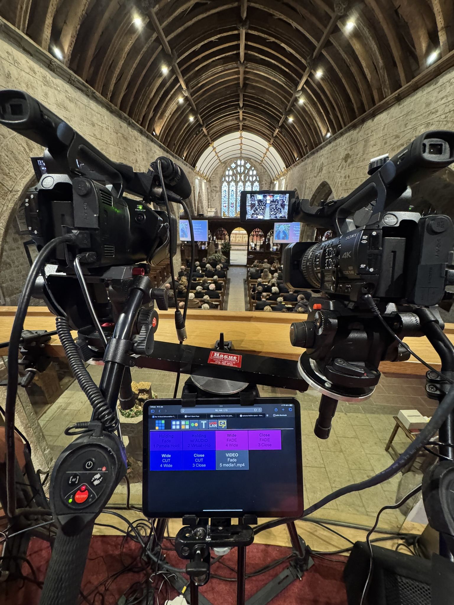 Two cameras and a vision-mixing laptop set up at the back of a church during a service