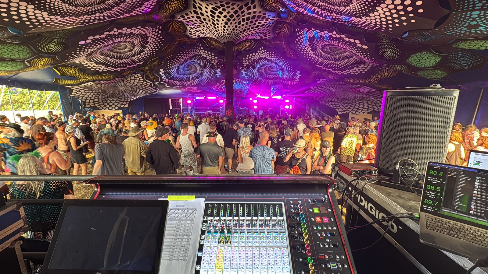 DiGiCo console front-of-house inside a festival tent with a large crowd and stage lighting