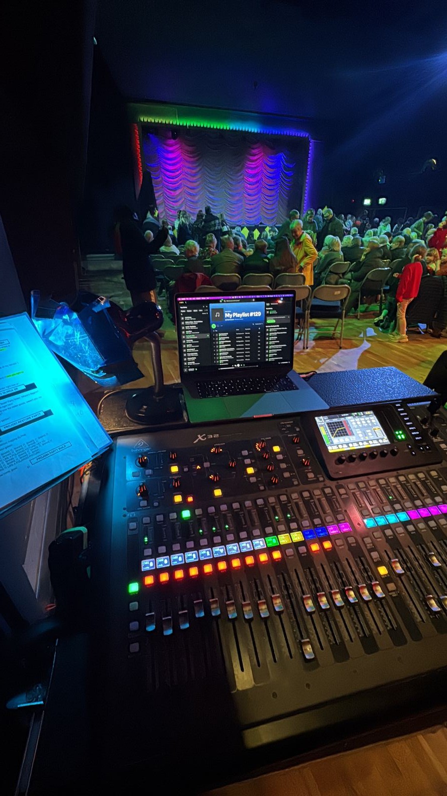 Behringer X32 console with laptop, facing a theatre stage and seated audience